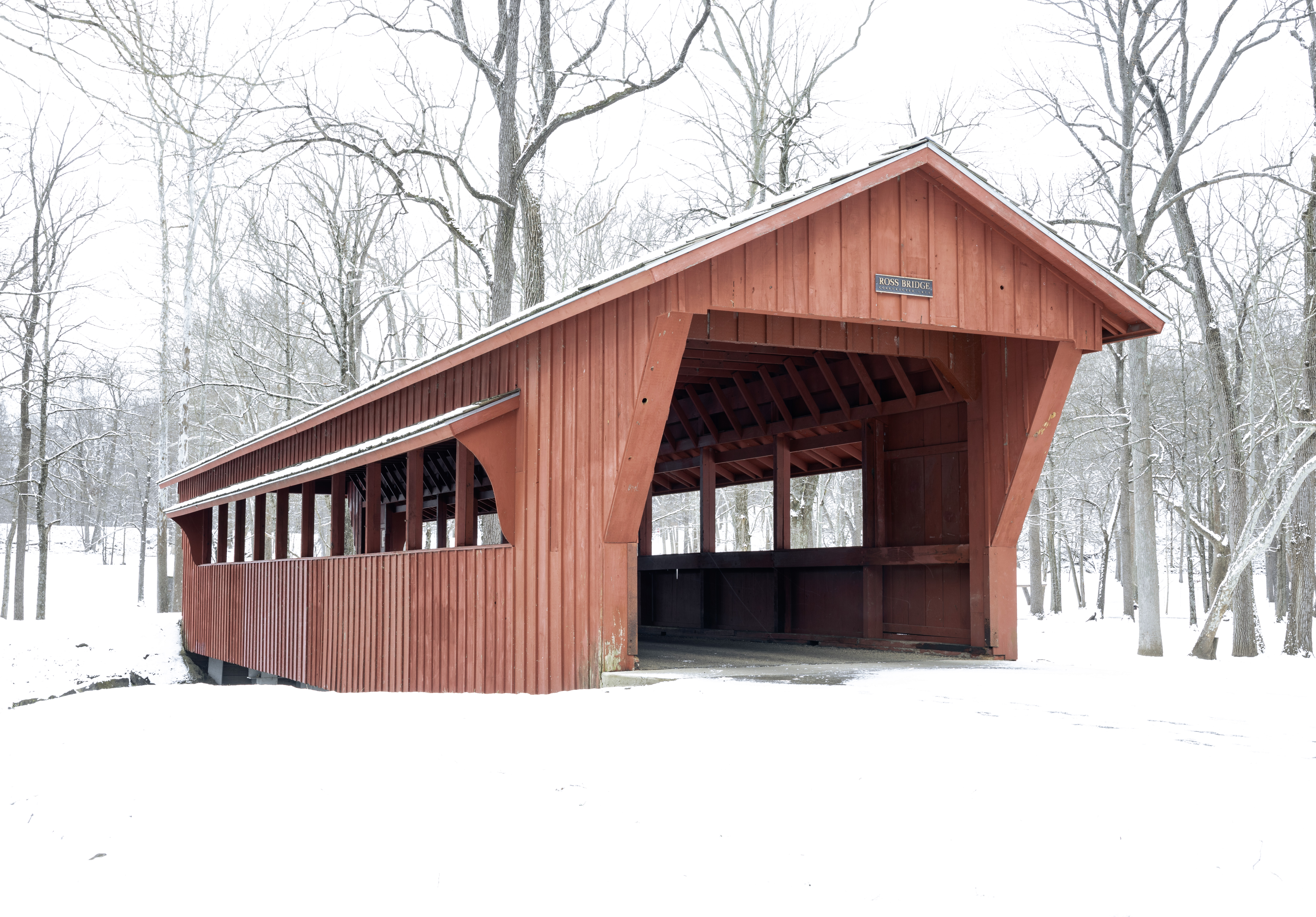 Ross Covered Bridge surrounded by fresh snow and bare woods at Tawawa Park in Sidney Ohio